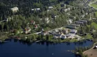 Aerial view of Dikemark in Norway - a few larger buildings nestled among trees, by the waterside.