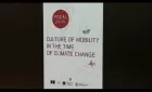 Still from Culture of Mobility in the Time of Climate Change video. Shows the title of the session projected onto a screen.