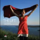 Cover of THE LIFT. Photo of a young woman standing on a clifftop, the sea behind her, holding over her head a red scarf which catches the wind.